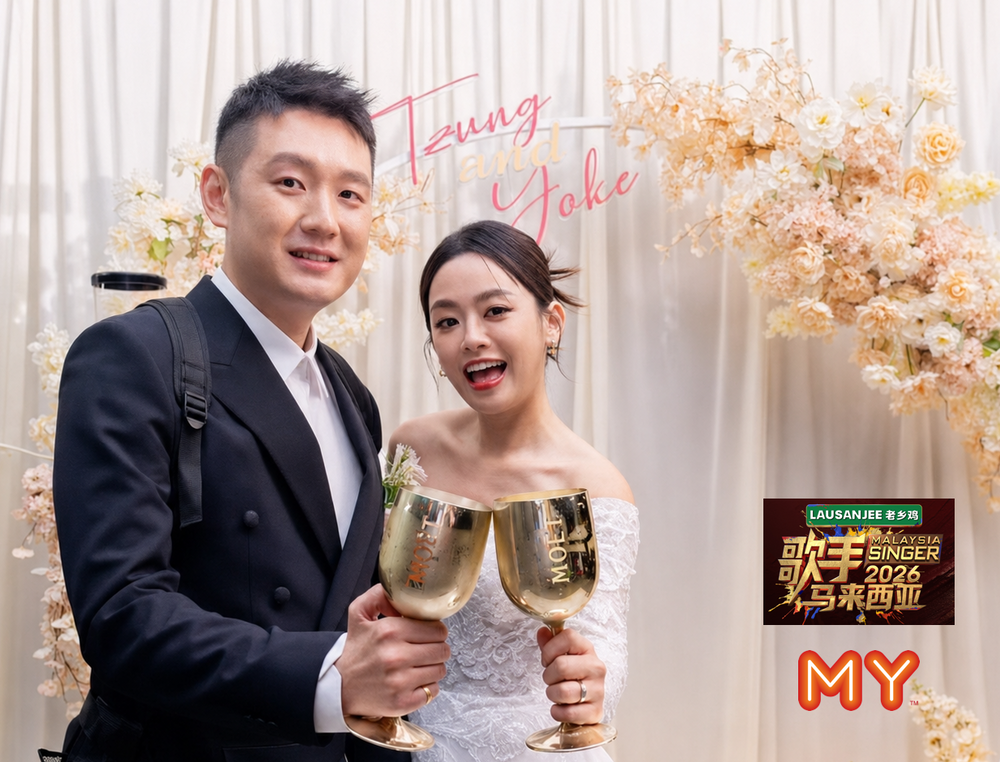 Tzung and Yoke celebrating at their Community Hall wedding backdrop with floral decor, white draping and personalised name sign