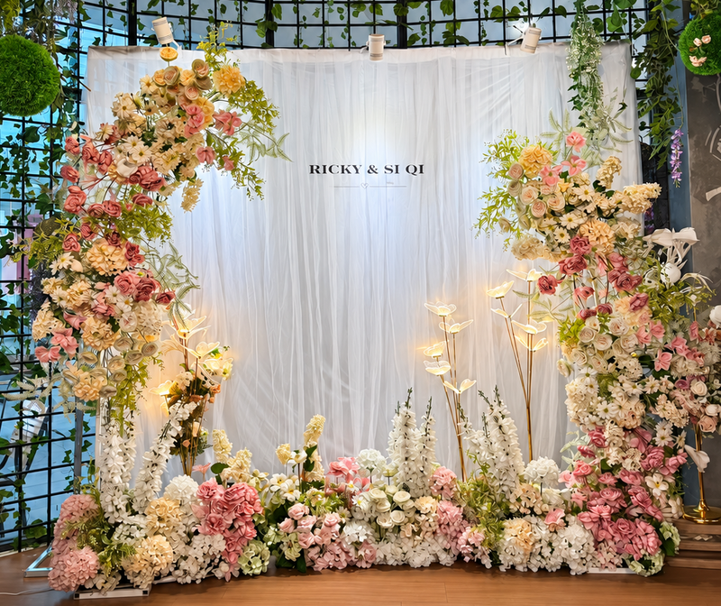 Ricky and Si Qi wedding backdrop with pink, white and cream flowers, greenery and warm illuminated stems